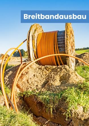 Kabeltrommel mit Breitbandrohren die in einem offenen Graben verlegt werden.